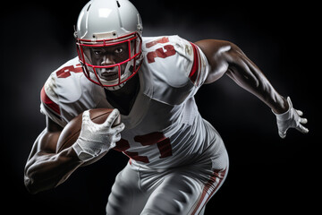 Portrait of American football player running with the ball. Muscular athlete in a white and red uniform with an ovoid ball in a dynamic pose. Isolated on black background.