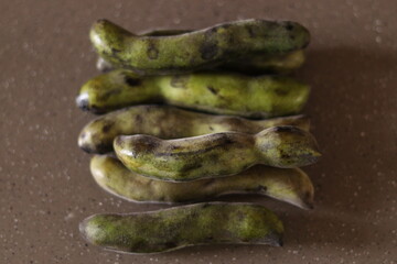 Bunch of Kewach or kenwach bean or thick french beans lying on the brown marble floor, aligned ...
