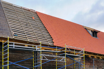 Installation of new clay tiles on new wooden battens on the roof of a historic house