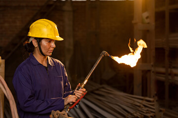 Female industrial worker working with blow torch in factory
