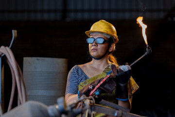 Female industrial worker working with blow torch in factory