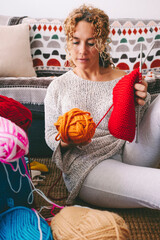 One woman at home sitting on the ground busy in knitting hobby work activity. Indoor leisure female people with wool. Creative time concept. Learning new things. Adult lady spending time in apartment