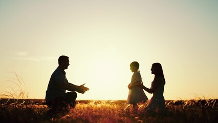 Father mother and daughter revelled in joy of evening in meadow surrounded by wheat field. Sun...
