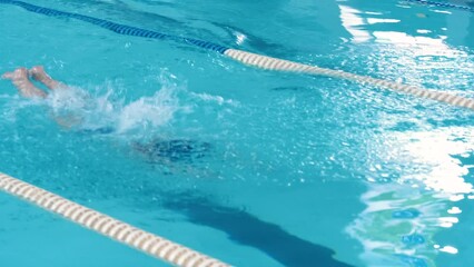 A young woman swimmer actively swims professionally in a sports pool using the butterfly technique. Athlete training.