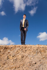 Businessman bravely walks along a rocky path toward the edge of a precipice