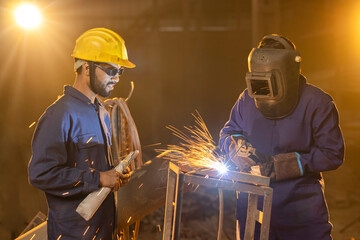 Industrial worker welding metal part at factory