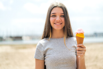 Teenager girl with a cornet ice cream at outdoors smiling a lot