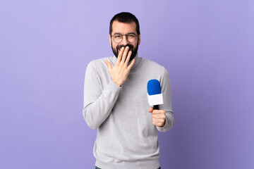 Adult reporter man with beard holding a microphone over isolated purple background happy and...