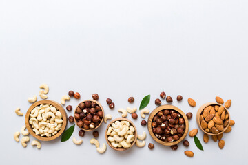 Assortment of nuts in wooden bowl on colored table. Cashew, hazelnuts, walnuts, almonds. Mix of nuts Top view with copy space