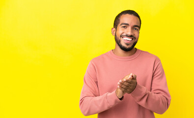 Young latin man isolated on yellow background applauding after presentation in a conference