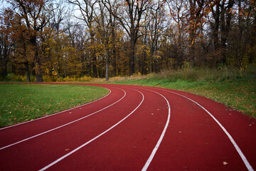 Red runninng race track with lanes at autumn park, Treadmill at stadium, Sport and fitness concept