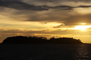 Silhouettes of coconut palm trees on tropical island at sunset, background for sea vacation and travel