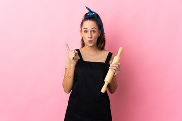 Young woman holding a rolling pin intending to realizes the solution while lifting a finger up - obrazy, fototapety, plakaty