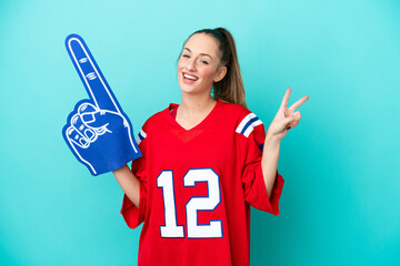 Young caucasian sport woman isolated on blue background smiling and showing victory sign