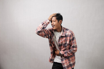 Asian young man in pink long shirt doing hand gesture holding dizzy head and stomach ache on...