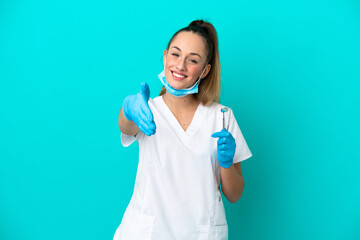 Dentist caucasian woman holding tools isolated on blue background shaking hands for closing a good...