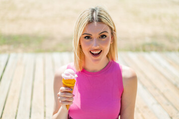 Young pretty blonde woman with a cornet ice cream at outdoors with surprise and shocked facial...