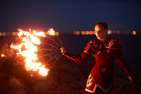 Waist up portrait of female performer dancing with fire fans outdoors at night, copy space - Powered by Adobe