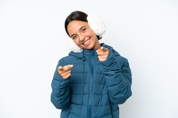 Young hispanic woman wearing a winter earmuffs isolated on white background points finger at you...