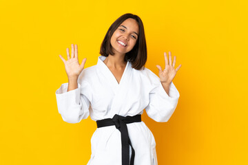 Young woman doing karate isolated on yellow background counting ten with fingers