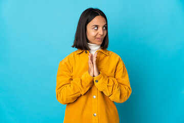 Young latin woman isolated on blue background scheming something