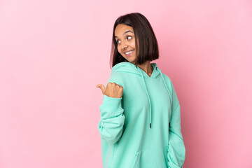 Fototapeta premium Young latin woman isolated on pink background pointing to the side to present a product