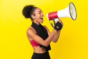 Young African sport woman isolated on yellow background shouting through a megaphone