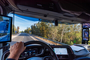 View from the driver's position of a truck on the road of the interior of the cabin with the screens as rearview mirrors and the GPS on the dashboard screen.