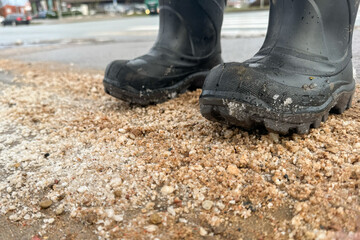 Standing with boots on a dirty street, salt and sand on the road in winter