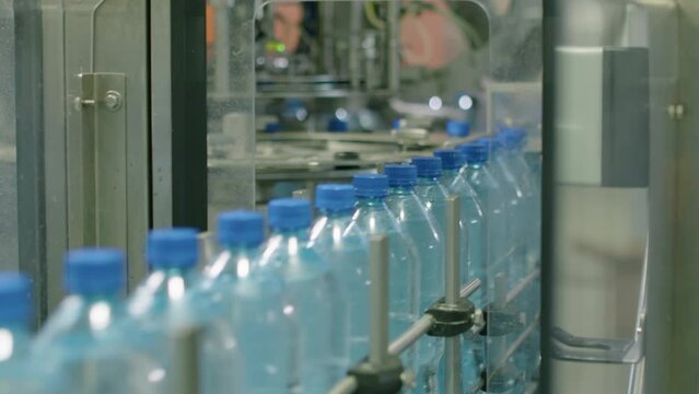 Handheld shot of conveyor line processing delivery of plastic bottles with pure distilled water at beverage factory