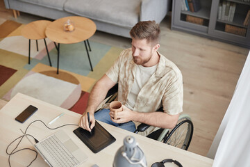 Top view at man with disability working at home office and editing photos or video with pen tablet,...