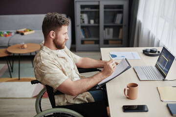Side view portrait of bearded man with disability designing mobile app while working from home