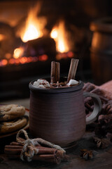 Mug of hot chocolate with fireplace burning in background