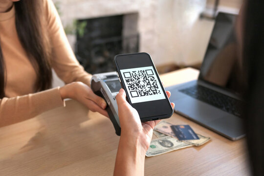 Young Asian woman smiling and paying with smartphone in restaurant