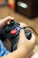Gamepad in the hands of a little boy. A boy plays computer games on a gamepad