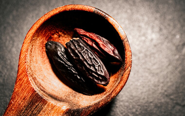 Tonka Beans in a wooden Spoon on a dark background