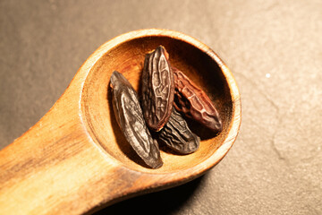 Tonka Beans in a wooden Spoon on a dark background