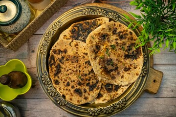 Sattu cucumber kulcha crispy wholesome and nutritious food served in a brass plate on a wooden table. This kulcha turns out crispy on the edges and soft on the inside from the cucumber, Healthy Kulcha