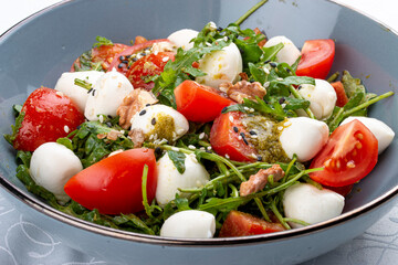 Caprese salad, cherry tomatoes, mozzarella, arugula and pesto sauce. Isolated image