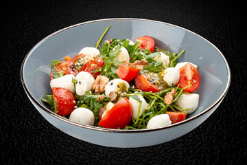 Caprese salad, cherry tomatoes, mozzarella, arugula and pesto sauce. Isolated image