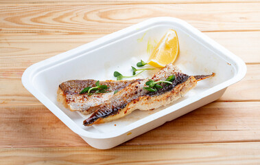 Sea bass fillet. Healthly food. Takeaway food. On a wooden background.