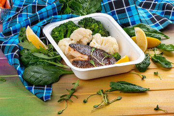Sea bass fillet, blanched broccoli and cauliflower. Healthly food. Takeaway food. On a wooden...
