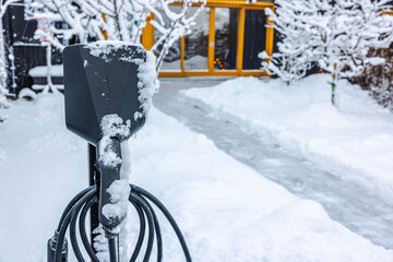 Close-up view of an electric vehicle charging station in a private parking area on a winter day....