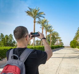 young man with a gray-red backpack behind his shoulders takes pi