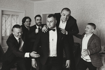 A young groom and his funny friends pose for the camera. A group of young people hug the groom and...