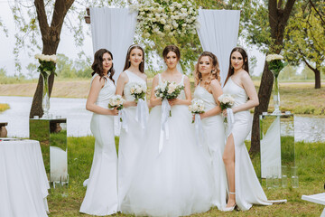 Group portrait of the bride and bridesmaids. Bride in a wedding dress and bridesmaids in white...