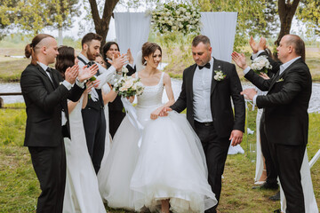 full-length portrait of the newlyweds and their friends at the wedding. The bride and groom with...