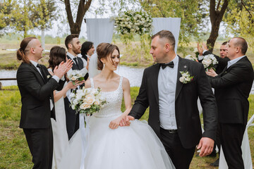 full-length portrait of the newlyweds and their friends at the wedding. The bride and groom with...