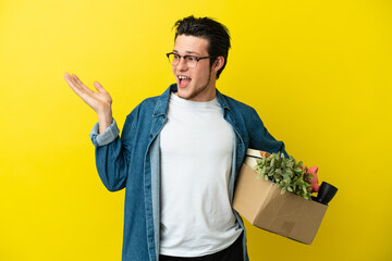 Russian Man making a move while picking up a box full of things isolated on yellow background...