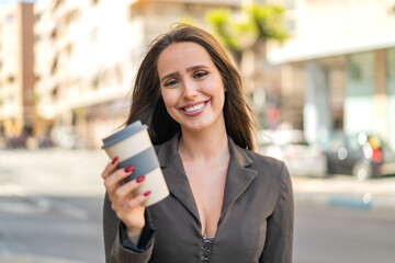 Young woman at outdoors holding a take away coffee with happy expression